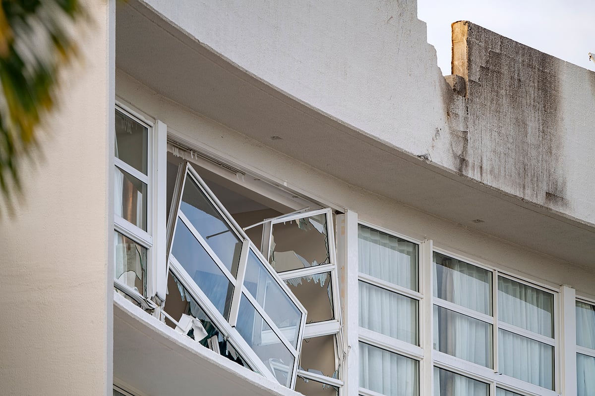 AP : A broken window hands precariously at the Double Tree by Hilton Hotel in Cairns, Australia, after a helicopter crashed into its roof early Monday, Aug. 12, 2024